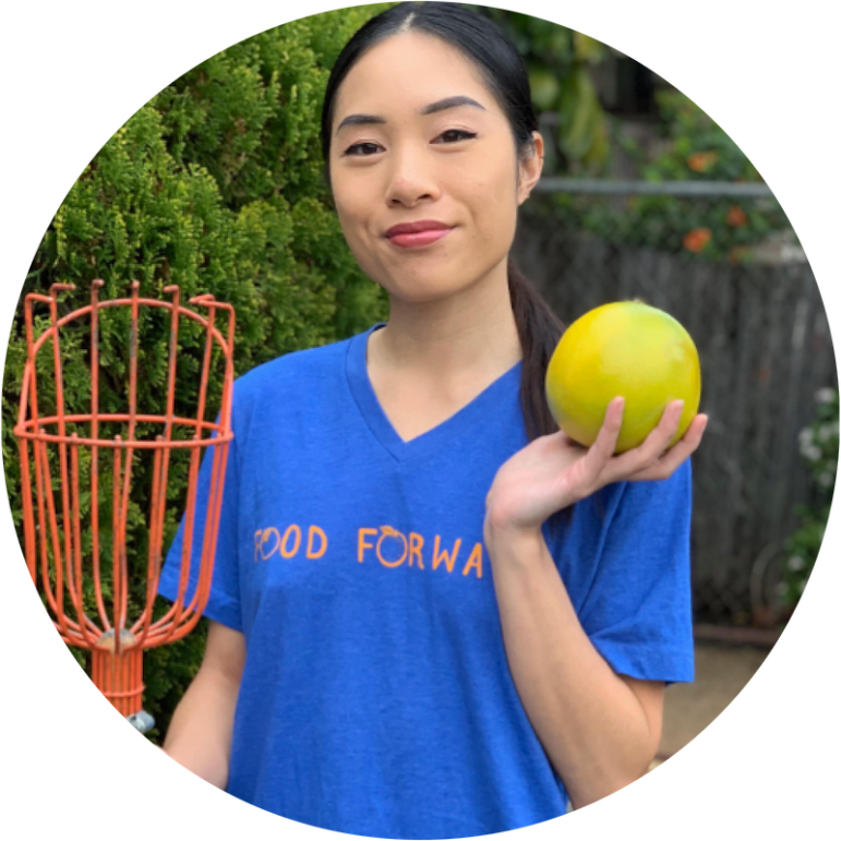 A Food Forward Pick Leader holds up a grapefruit