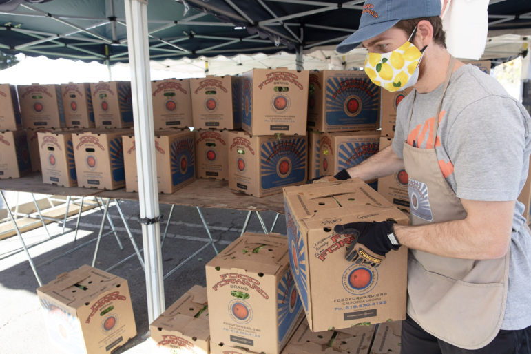 A volunteer at a farmers market moves Food Forward boxes