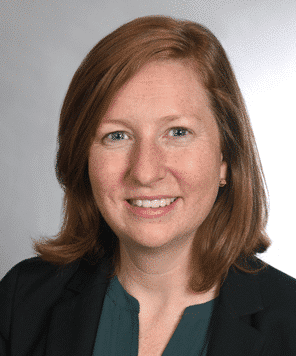 Betsy O' Brien smiling in front of grey background