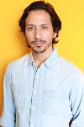 Kevin in light blue shirt in front of orange/yellow background