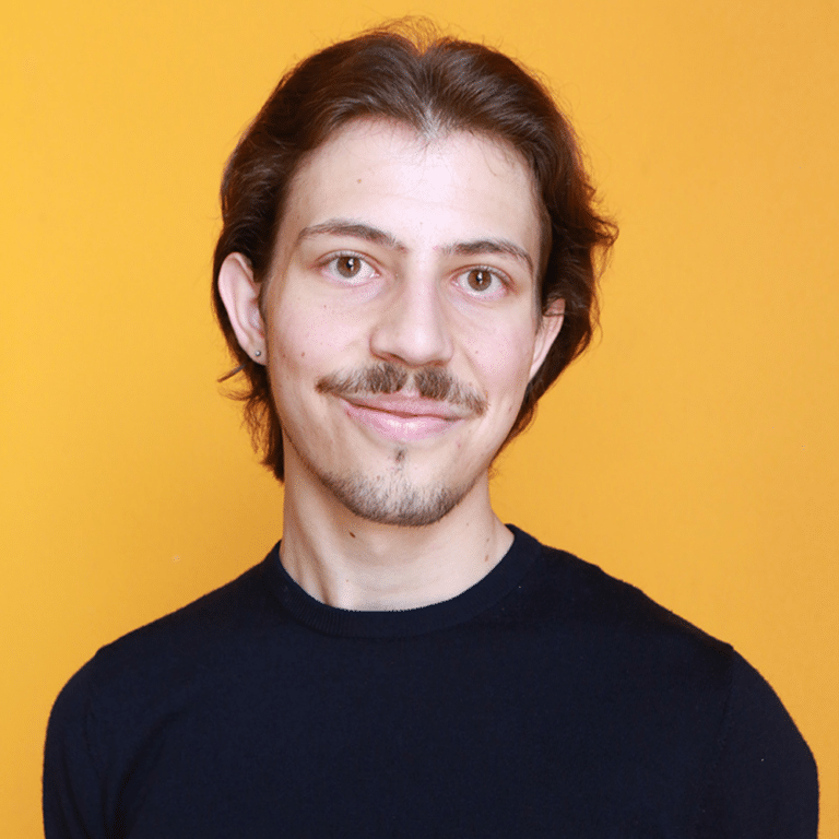 Michael smiling in front of orange background