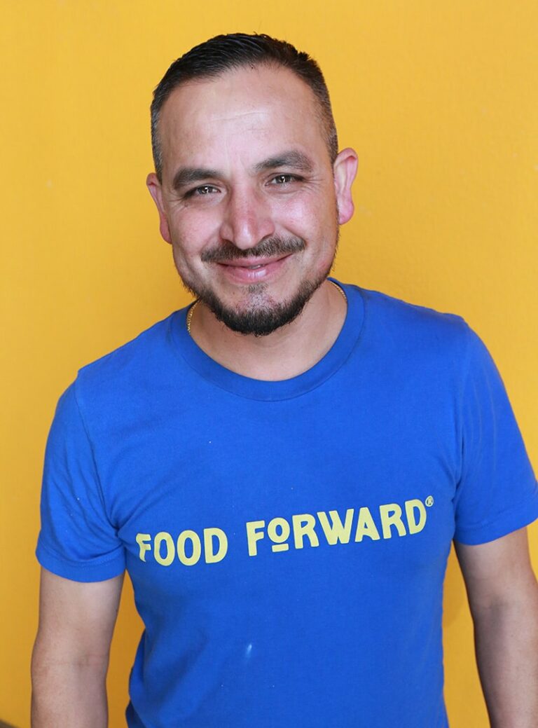 Jorge smiling in front of orange background