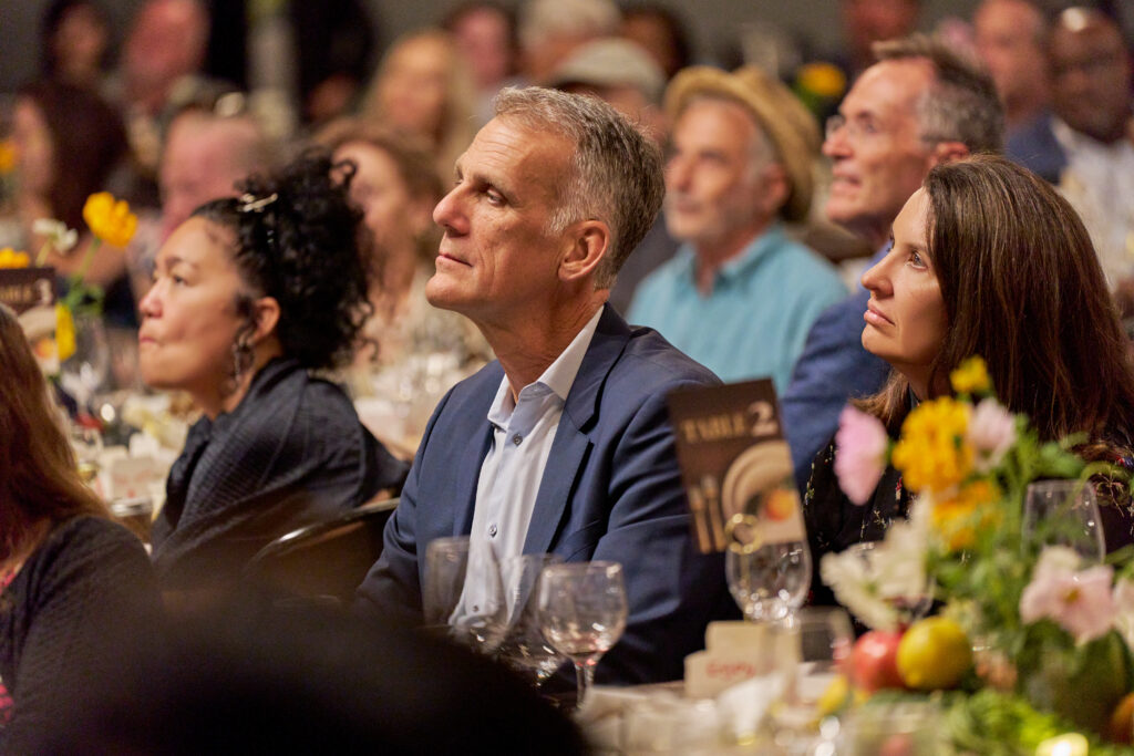 guests seated at a table watch a presentation at food forward’s tomorrow’s table event.