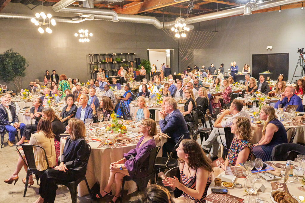 guests seated at round tables watch a presentation at food forward’s tomorrow’s table event.